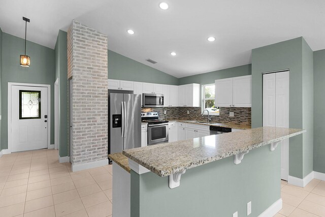 2867 SW Mustang Ter, Stuart, FL 34997 - kitchen featuring appliances with stainless steel finishes, lofted ceiling, decorative backsplash, a breakfast bar area, and white cabinetry