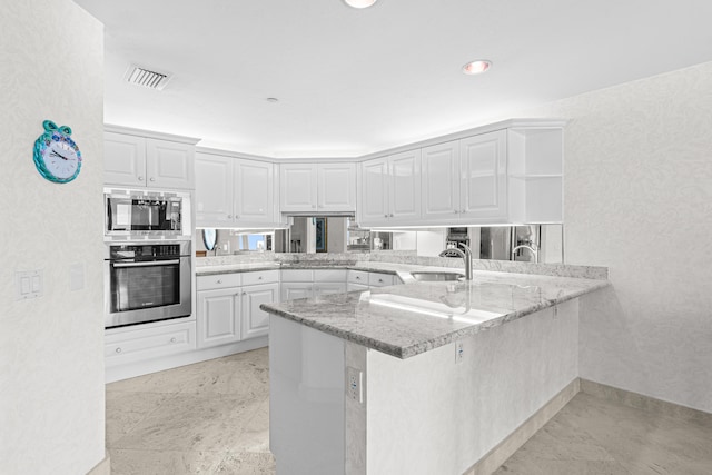 800 Ocean Dr Unit 204, Juno Beach, FL 33408 - kitchen with stainless steel appliances, open shelves, a peninsula, a sink, and white cabinetry