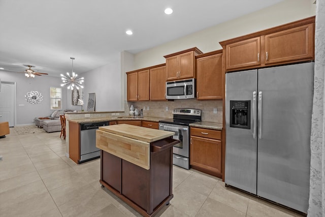 474 Francesca Ridge Rd, Boynton Beach, FL 33435 - kitchen featuring appliances with stainless steel finishes, a peninsula, backsplash, brown cabinets, and light tile patterned floors