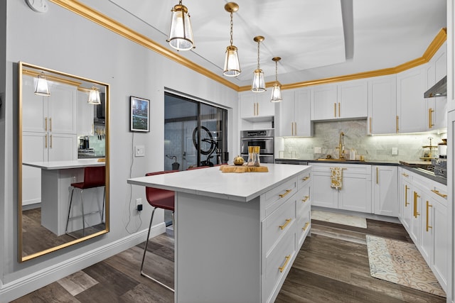1508 15th Ter, Palm Beach Gardens, FL 33418 - kitchen with a center island, decorative backsplash, white cabinetry, a breakfast bar, and dark wood-style flooring