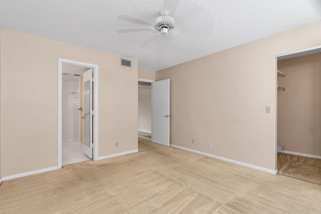 531 Shady Pine Way Unit A 2, Greenacres, FL 33415 - unfurnished bedroom featuring light carpet, a closet, a walk in closet, baseboards, and a textured ceiling
