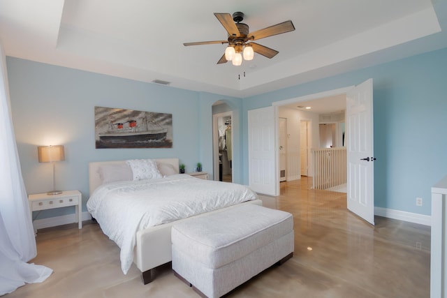 1026 Center Stone Ln, Riviera Beach, FL 33404 - bedroom featuring a tray ceiling, arched walkways, finished concrete flooring, a spacious closet, and ceiling fan