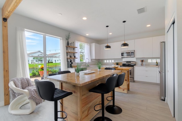 1026 Center Stone Ln, Riviera Beach, FL 33404 - kitchen with appliances with stainless steel finishes, decorative light fixtures, white cabinetry, light wood-style floors, and recessed lighting
