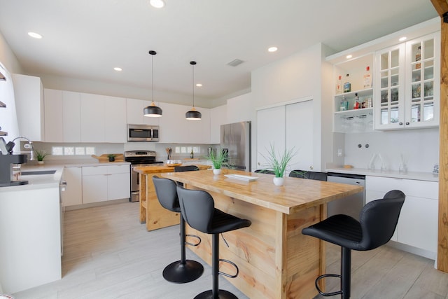 1026 Center Stone Ln, Riviera Beach, FL 33404 - kitchen featuring stainless steel appliances, wooden counters, a kitchen island, a breakfast bar area, and white cabinets