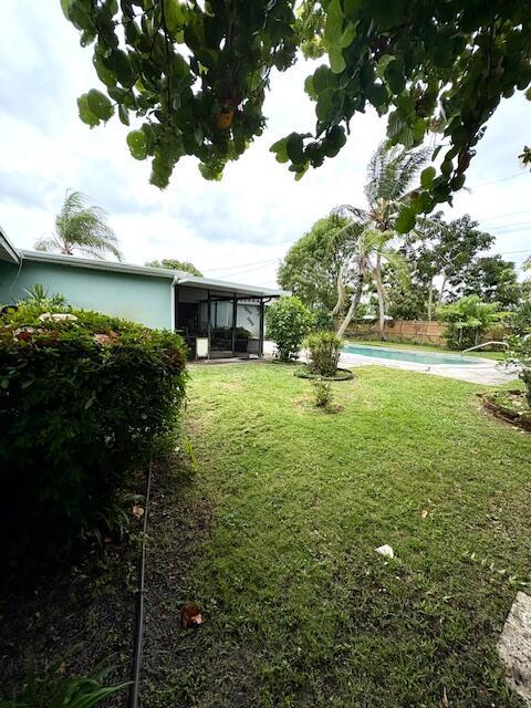 729 W Kalmia Dr, Lake Park, FL 33403 - view of grassy yard featuring an outdoor pool