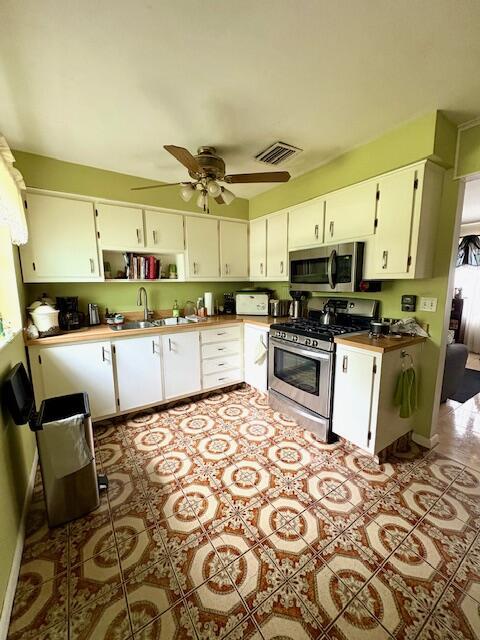 729 W Kalmia Dr, Lake Park, FL 33403 - kitchen featuring appliances with stainless steel finishes, tile patterned floors, and white cabinetry