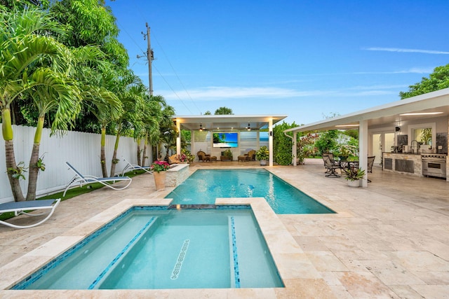 936 Upland Rd, West Palm Beach, FL 33401 - view of swimming pool featuring an outdoor kitchen, a patio, a ceiling fan, a fenced backyard, and a pool with connected hot tub