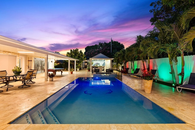936 Upland Rd, West Palm Beach, FL 33401 - pool at dusk with a fenced backyard, a gazebo, a patio area, and a pool with connected hot tub
