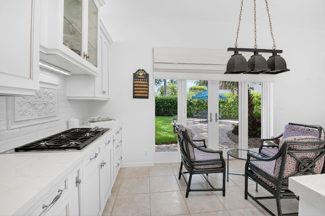 2373 NW 25th Way, Boca Raton, FL 33434 - kitchen featuring stainless steel gas stovetop, backsplash, white cabinets, light stone countertops, and glass insert cabinets