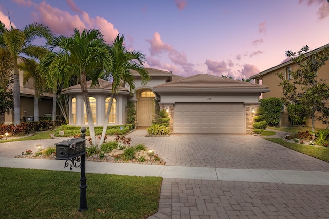 725 Edgebrook Ln, West Palm Beach, FL 33411 - view of front of house featuring decorative driveway, an attached garage, stucco siding, stone siding, and a tile roof