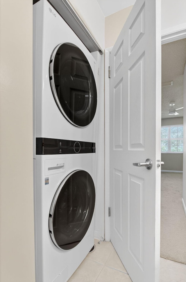 3131 Clint Moore Rd Unit 206, Boca Raton, FL 33496 - laundry area featuring stacked washer and clothes dryer, tile patterned floors, and baseboards