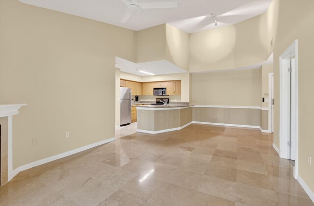 3131 Clint Moore Rd Unit 206, Boca Raton, FL 33496 - unfurnished living room with a towering ceiling, baseboards, a ceiling fan, a tiled fireplace, and a wainscoted wall