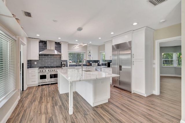 1220 N Swinton Ave, Delray Beach, FL 33444 - kitchen with high quality appliances, wall chimney range hood, a sink, decorative backsplash, and white cabinetry