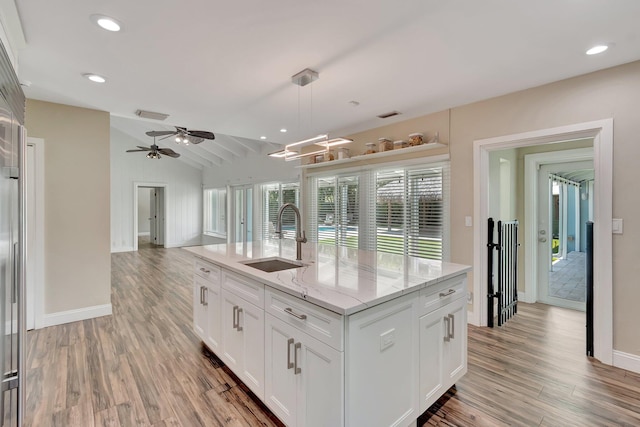 1220 N Swinton Ave, Delray Beach, FL 33444 - kitchen with a sink, light wood-style floors, vaulted ceiling, light stone countertops, and white cabinets