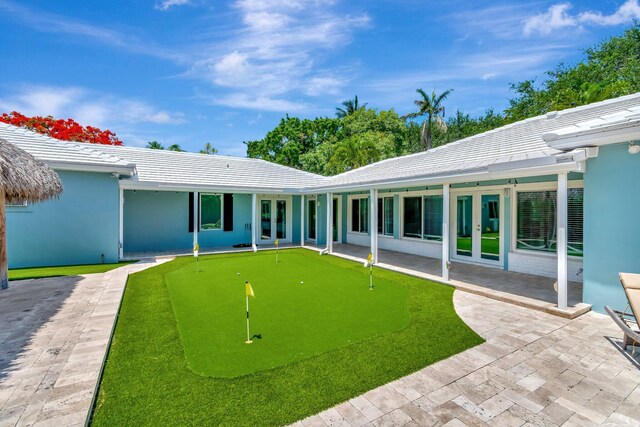 1220 N Swinton Ave, Delray Beach, FL 33444 - rear view of property featuring french doors, an area to practice putting, and a patio