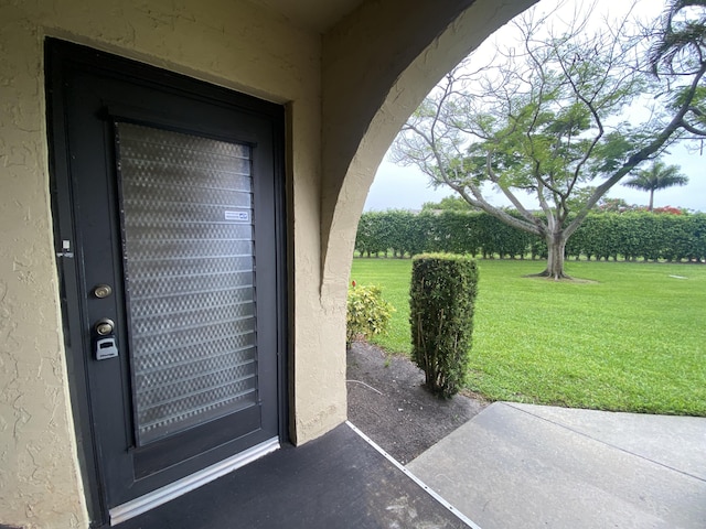 302 Pine Ridge Cir Unit D-1, Greenacres, FL 33463 - doorway to property with stucco siding, a yard, and a patio