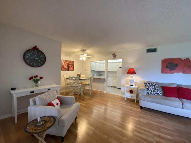 302 Pine Ridge Cir Unit D-1, Greenacres, FL 33463 - living room with a ceiling fan, light wood-style flooring, a textured ceiling, and baseboards