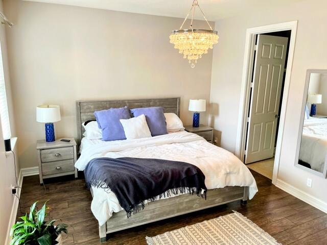 110 W Coda Cir Unit 110, Delray Beach, FL 33444 - bedroom featuring baseboards, wood finished floors, and a chandelier