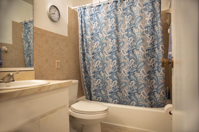 2511 SE Marius St, Port Saint Lucie, FL 34953 - bathroom featuring tile walls, vanity, shower / bath combo with shower curtain, toilet, and wainscoting
