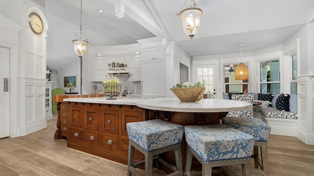 6000 Eagles Nest Dr, Jupiter, FL 33458 - kitchen featuring vaulted ceiling, light wood finished floors, white cabinets, a spacious island, and hanging light fixtures
