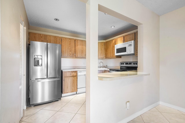 521 Shady Pine Way Unit C2, Greenacres, FL 33415 - kitchen featuring stainless steel appliances, light countertops, light tile patterned floors, baseboards, and a textured ceiling