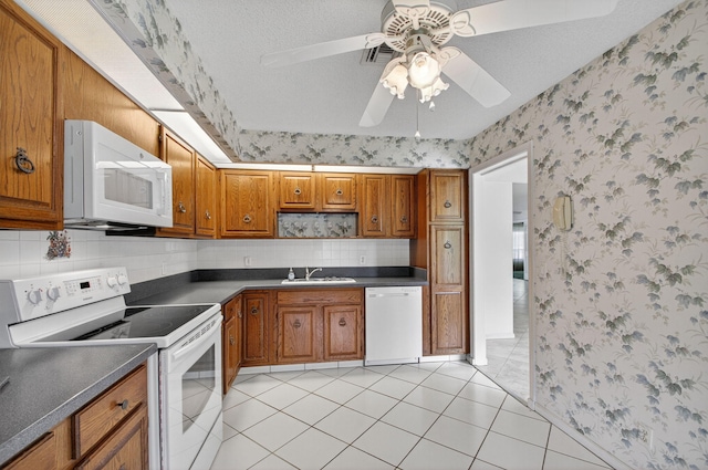 3946 Quail Ridge Dr N, Boynton Beach, FL 33436 - kitchen featuring white appliances, wallpapered walls, dark countertops, and brown cabinetry