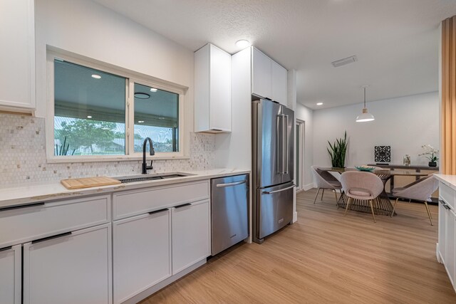 18085 102nd Way S, Boca Raton, FL 33498 - kitchen featuring stainless steel appliances, white cabinetry, light wood-type flooring, tasteful backsplash, and light countertops