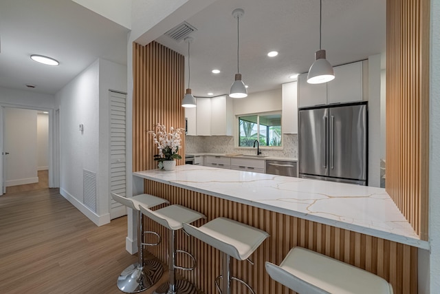 18085 102nd Way S, Boca Raton, FL 33498 - kitchen with stainless steel appliances, a peninsula, white cabinetry, light stone countertops, and light wood-type flooring