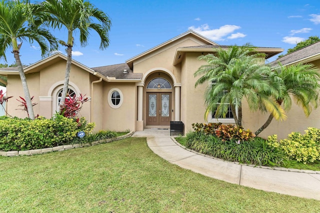 2450 SW Summit St, Port Saint Lucie, FL 34984 - view of front of home featuring french doors, stucco siding, and a front lawn