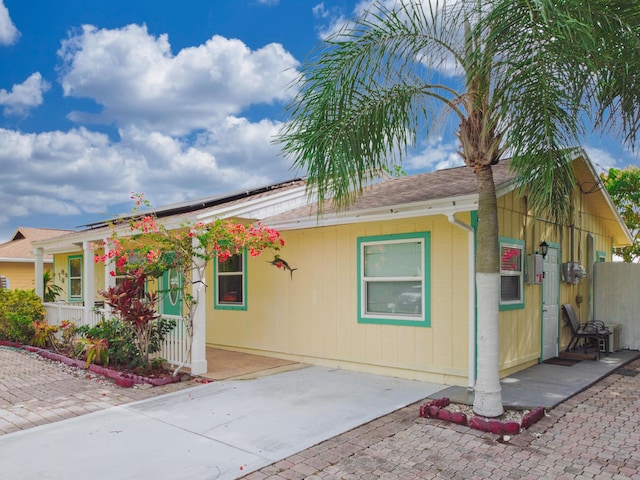 1913 SW Idaho Ln, Port Saint Lucie, FL 34953 - view of front of house featuring a porch, roof mounted solar panels, and a shingled roof