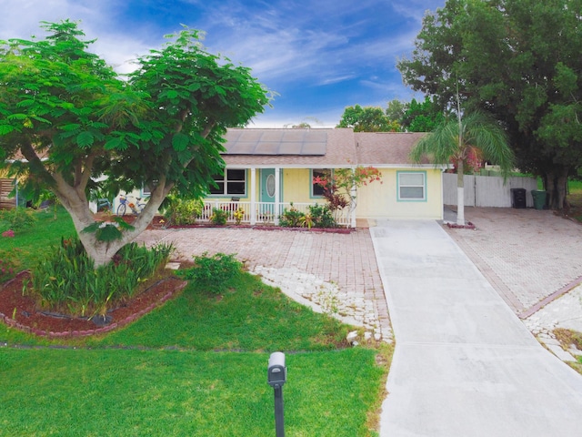 1913 SW Idaho Ln, Port Saint Lucie, FL 34953 - ranch-style house with covered porch, solar panels, driveway, a shingled roof, and a front yard