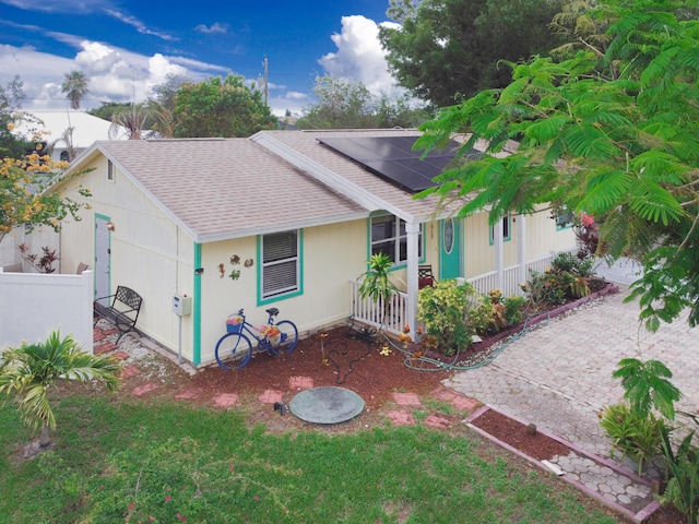 1913 SW Idaho Ln, Port Saint Lucie, FL 34953 - view of front facade with roof with shingles, roof mounted solar panels, and a porch