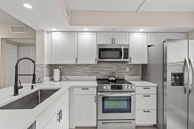 12829 Briarlake Dr Unit 102, Palm Beach Gardens, FL 33418 - kitchen featuring appliances with stainless steel finishes, a sink, white cabinets, tasteful backsplash, and recessed lighting