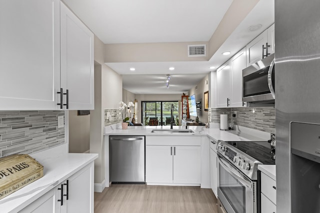 12829 Briarlake Dr Unit 102, Palm Beach Gardens, FL 33418 - kitchen featuring appliances with stainless steel finishes, a sink, recessed lighting, tasteful backsplash, and light wood-style floors