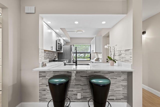 12829 Briarlake Dr Unit 102, Palm Beach Gardens, FL 33418 - kitchen featuring a peninsula, stainless steel microwave, decorative backsplash, and recessed lighting