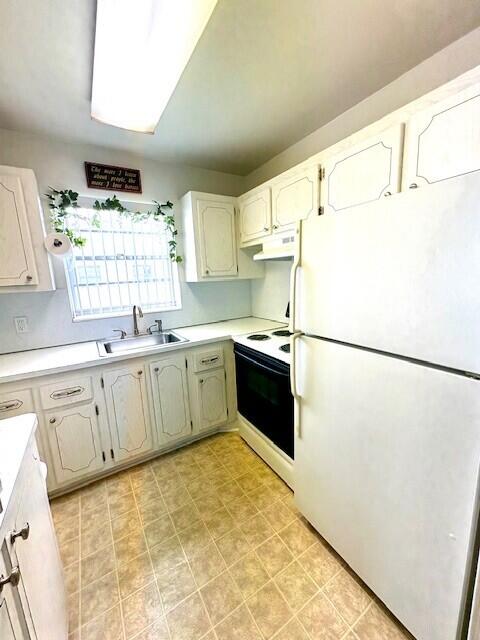 127 Berkshire F, West Palm Beach, FL 33417 - kitchen with white appliances, a sink, under cabinet range hood, and light countertops