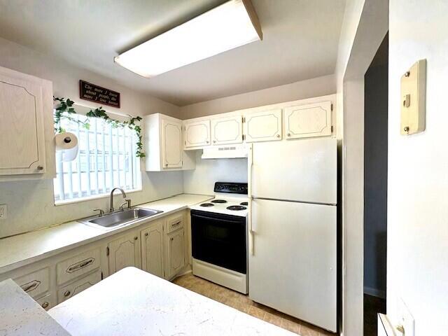 127 Berkshire F, West Palm Beach, FL 33417 - kitchen with white appliances, a sink, light countertops, under cabinet range hood, and white cabinetry