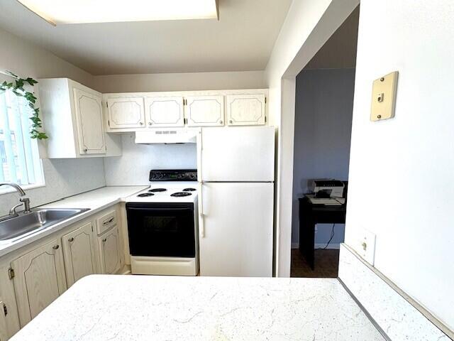 127 Berkshire F, West Palm Beach, FL 33417 - kitchen featuring white appliances, a sink, under cabinet range hood, light countertops, and white cabinets