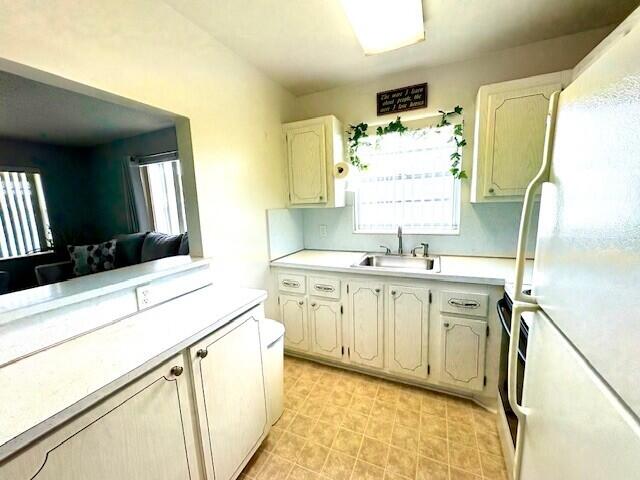 127 Berkshire F, West Palm Beach, FL 33417 - kitchen with freestanding refrigerator, a sink, light countertops, and healthy amount of natural light