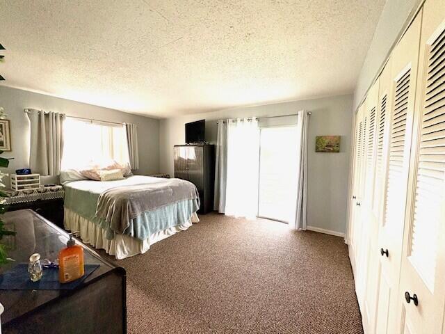 127 Berkshire F, West Palm Beach, FL 33417 - bedroom with carpet floors, a textured ceiling, and a closet