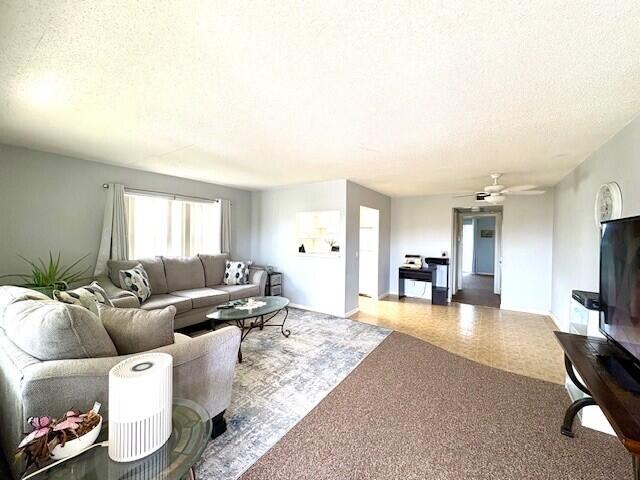 127 Berkshire F, West Palm Beach, FL 33417 - living area featuring baseboards, a ceiling fan, and a textured ceiling