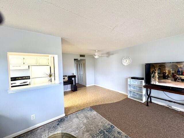 127 Berkshire F, West Palm Beach, FL 33417 - living room with a ceiling fan, baseboards, and a textured ceiling