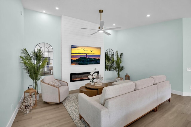 889 SW Balmoral Trce, Stuart, FL 34997 - living room with light wood-type flooring, a large fireplace, recessed lighting, baseboards, and a ceiling fan