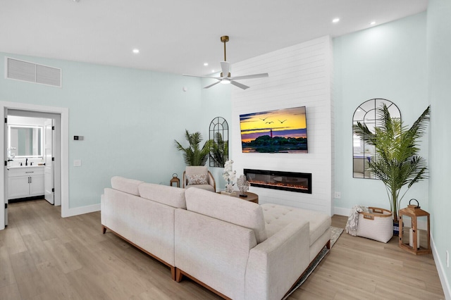889 SW Balmoral Trce, Stuart, FL 34997 - living room with light wood-type flooring, a glass covered fireplace, recessed lighting, baseboards, and ceiling fan