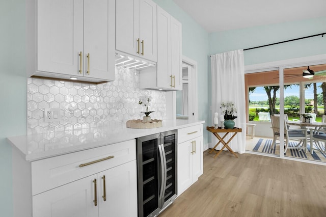 889 SW Balmoral Trce, Stuart, FL 34997 - kitchen featuring beverage cooler, light countertops, light wood-style floors, decorative backsplash, and white cabinets