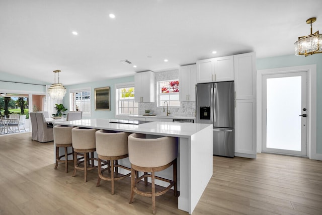 889 SW Balmoral Trce, Stuart, FL 34997 - kitchen with stainless steel refrigerator with ice dispenser, a chandelier, a center island, light countertops, and decorative backsplash