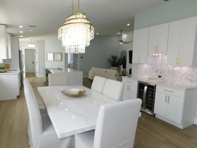 889 SW Balmoral Trce, Stuart, FL 34997 - dining area with wine cooler, light wood-style flooring, recessed lighting, ceiling fan, and a chandelier