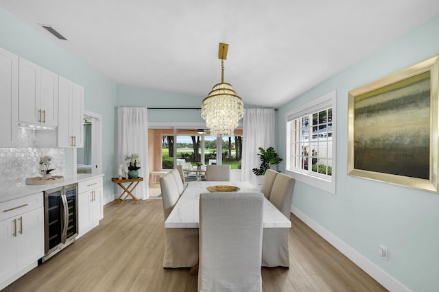 889 SW Balmoral Trce, Stuart, FL 34997 - dining room featuring wine cooler, a chandelier, healthy amount of natural light, light wood-type flooring, and vaulted ceiling