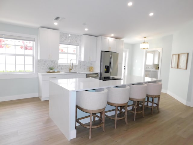 889 SW Balmoral Trce, Stuart, FL 34997 - kitchen featuring stainless steel appliances, a center island, light wood-style floors, a kitchen breakfast bar, and white cabinetry