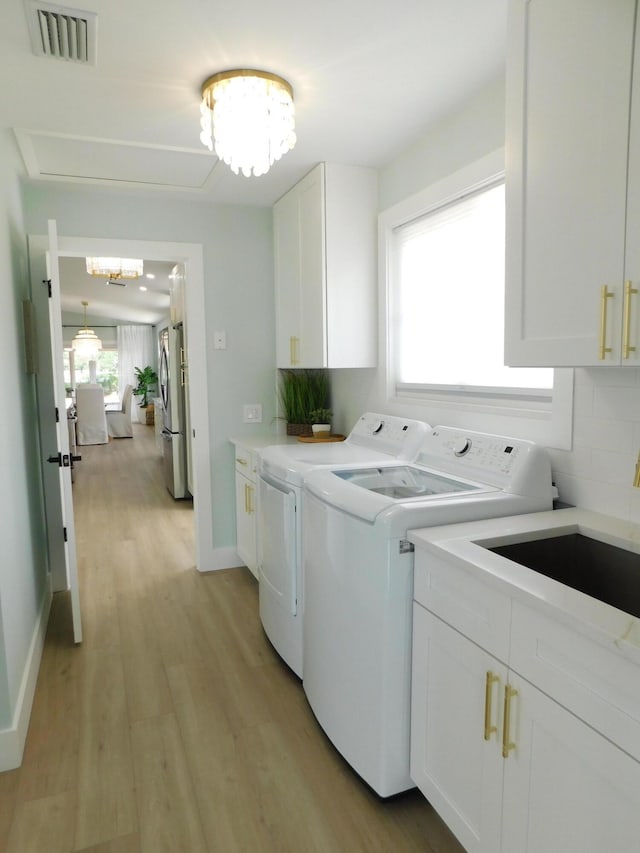889 SW Balmoral Trce, Stuart, FL 34997 - laundry room with independent washer and dryer, cabinet space, a chandelier, and light wood-style floors